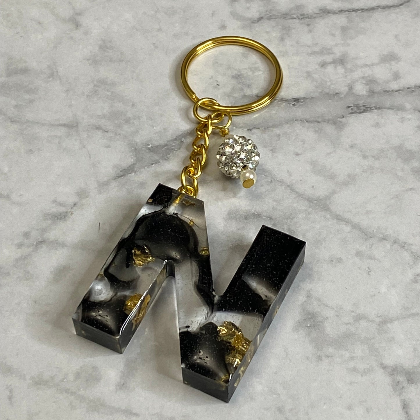 Letter N of The Clear Resin Alphabet Letter Keychain with Gold Flake and Black Accents