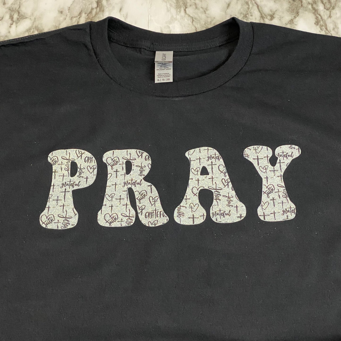 Close Up of Glittery PRAY with Black and White Cross Pattern T-Shirt