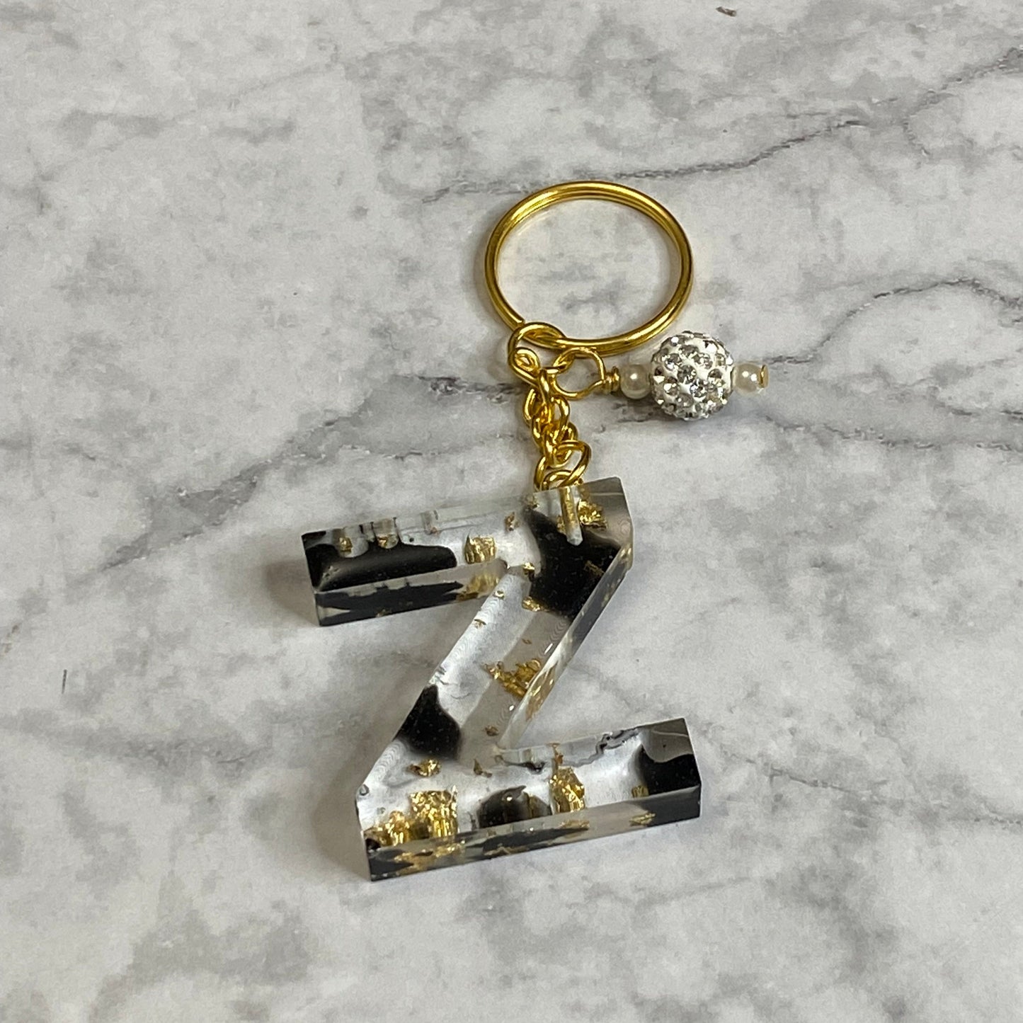 Letter Z of The Clear Resin Alphabet Letter Keychain with Gold Flake and Black Accents