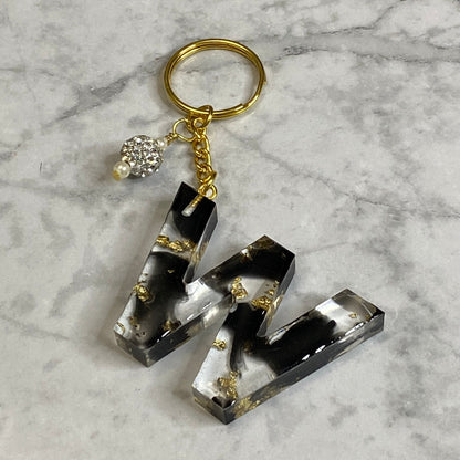 Letter W of The Clear Resin Alphabet Letter Keychain with Gold Flake and Black Accents