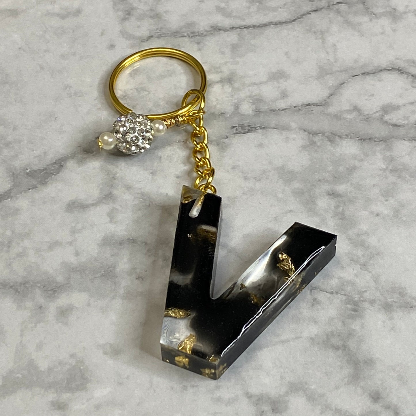 Letter V of The Clear Resin Alphabet Letter Keychain with Gold Flake and Black Accents