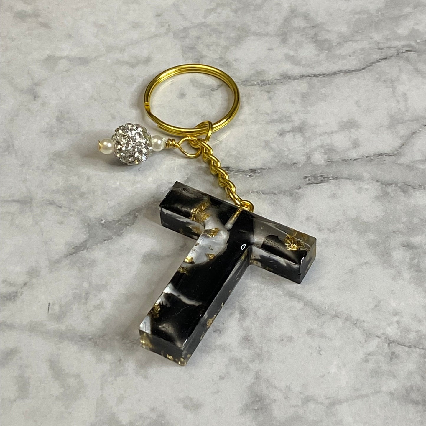 Letter T of The Clear Resin Alphabet Letter Keychain with Gold Flake and Black Accents