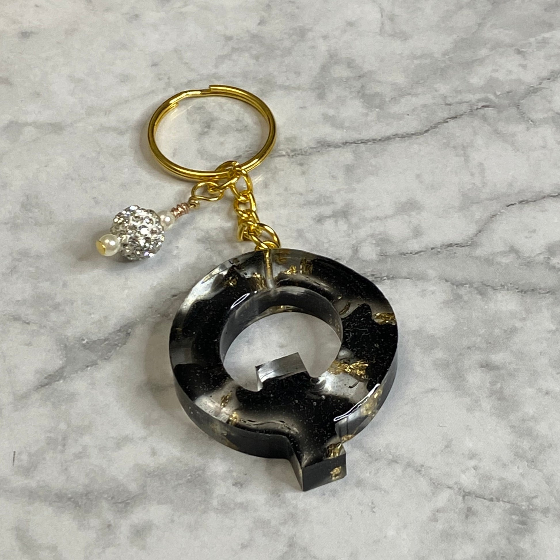 Letter Q of The Clear Resin Alphabet Letter Keychain with Gold Flake and Black Accents