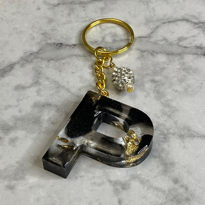 Letter P of The Clear Resin Alphabet Letter Keychain with Gold Flake and Black Accents