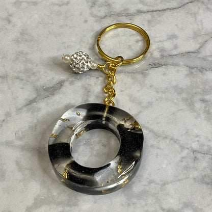 Letter O of The Clear Resin Alphabet Letter Keychain with Gold Flake and Black Accents