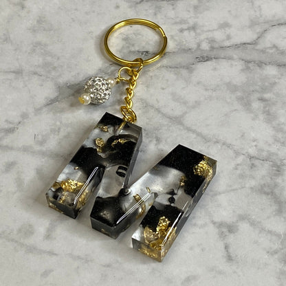 Letter M of The Clear Resin Alphabet Letter Keychain with Gold Flake and Black Accents