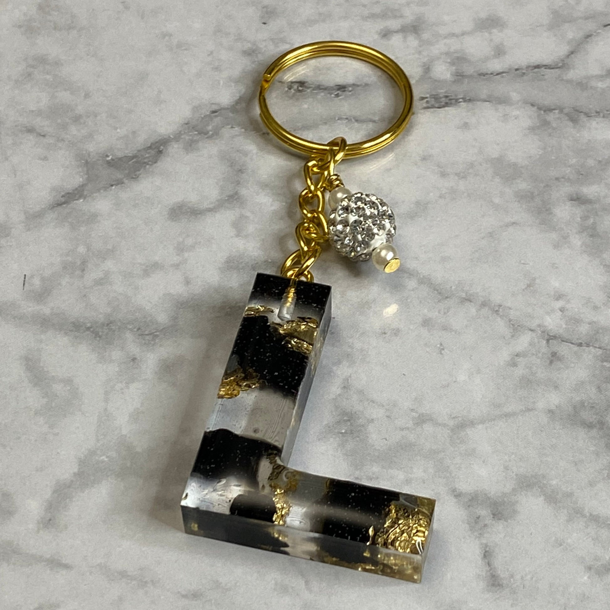 Letter L of The Clear Resin Alphabet Letter Keychain with Gold Flake and Black Accents