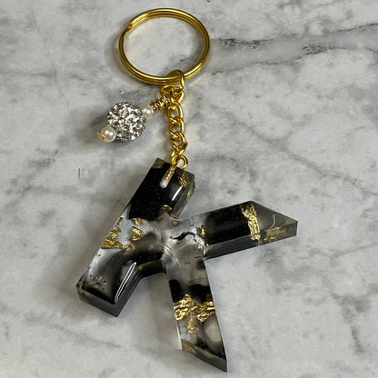 Letter K of The Clear Resin Alphabet Letter Keychain with Gold Flake and Black Accents