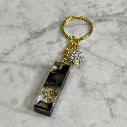 Letter I of The Clear Resin Alphabet Letter Keychain with Gold Flake and Black Accents