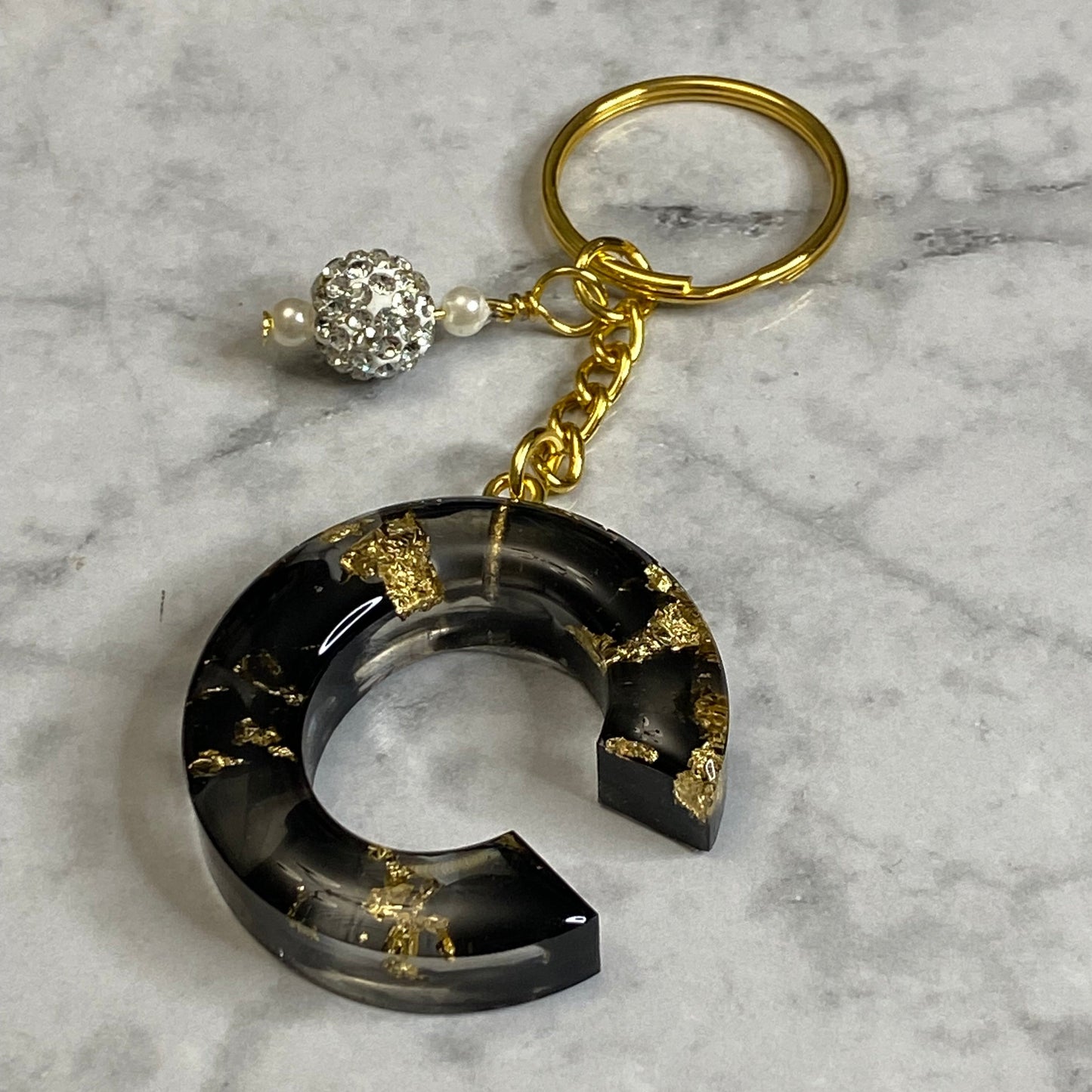 Letter C of The Clear Resin Alphabet Letter Keychain with Gold Flake and Black Accents