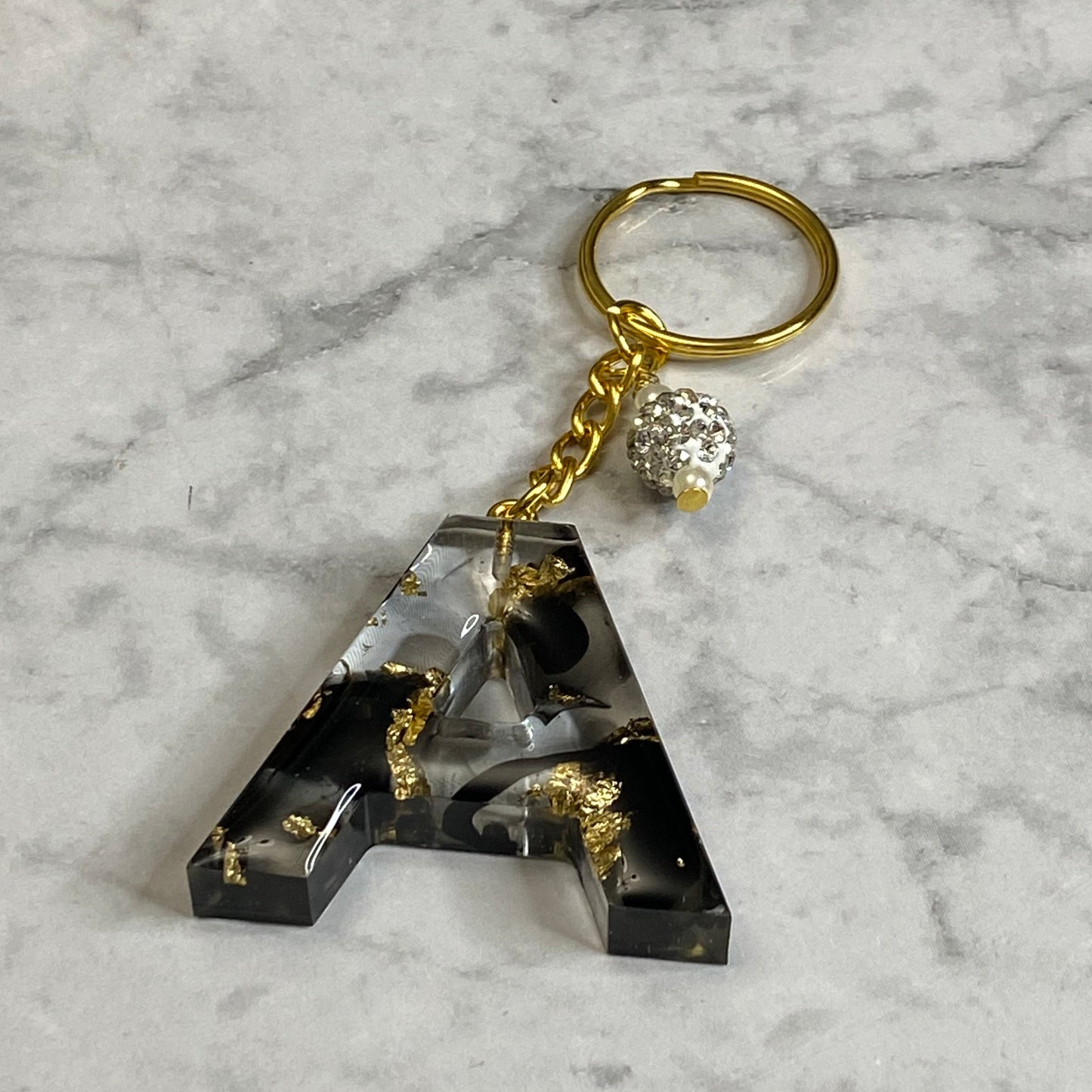 Letter A of The Clear Resin Alphabet Letter Keychain with Gold Flake and Black Accents